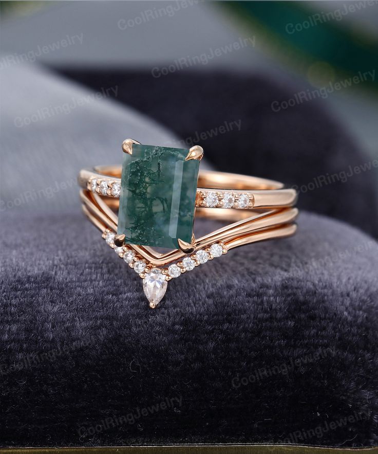 an emerald and diamond ring set on top of a velvet cushion with diamonds around it