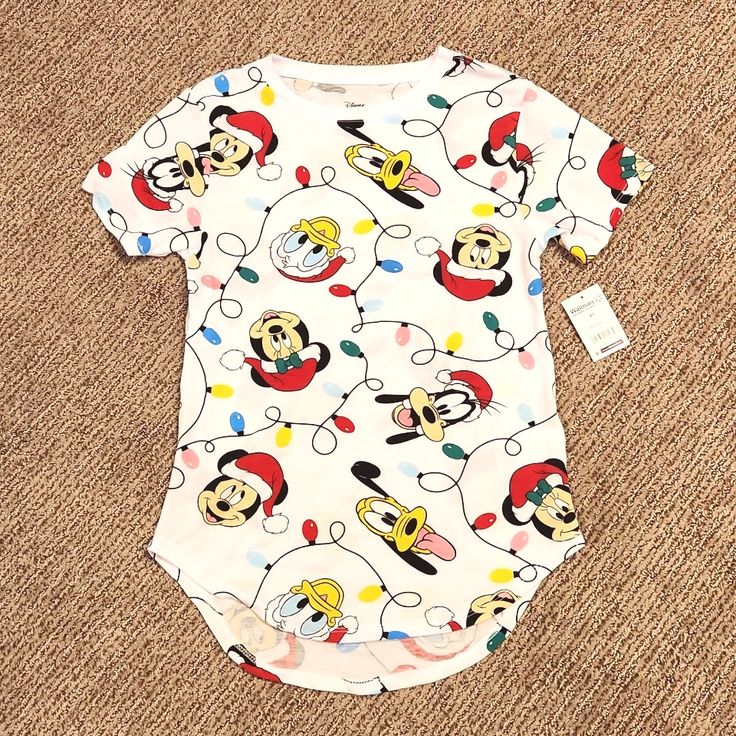 Disney Characters Christmas Tee Shirt Details: Lightweight Fabric Made Of Polyester/Rayon Blend Allover Character Print Scalloped Hem Short Sleeve Crew Neck White Christmas Tops With Cartoon Print, White Christmas Cartoon Print Tops, White Cartoon Print Tops For Christmas, Playful Cotton Holiday Tops, White Tops With Cartoon Print For Christmas, Playful Cotton Tops For The Holiday Season, Playful Cotton Christmas Top, Holiday Cotton Tops With Character Print, Holiday Cotton Top With Character Print