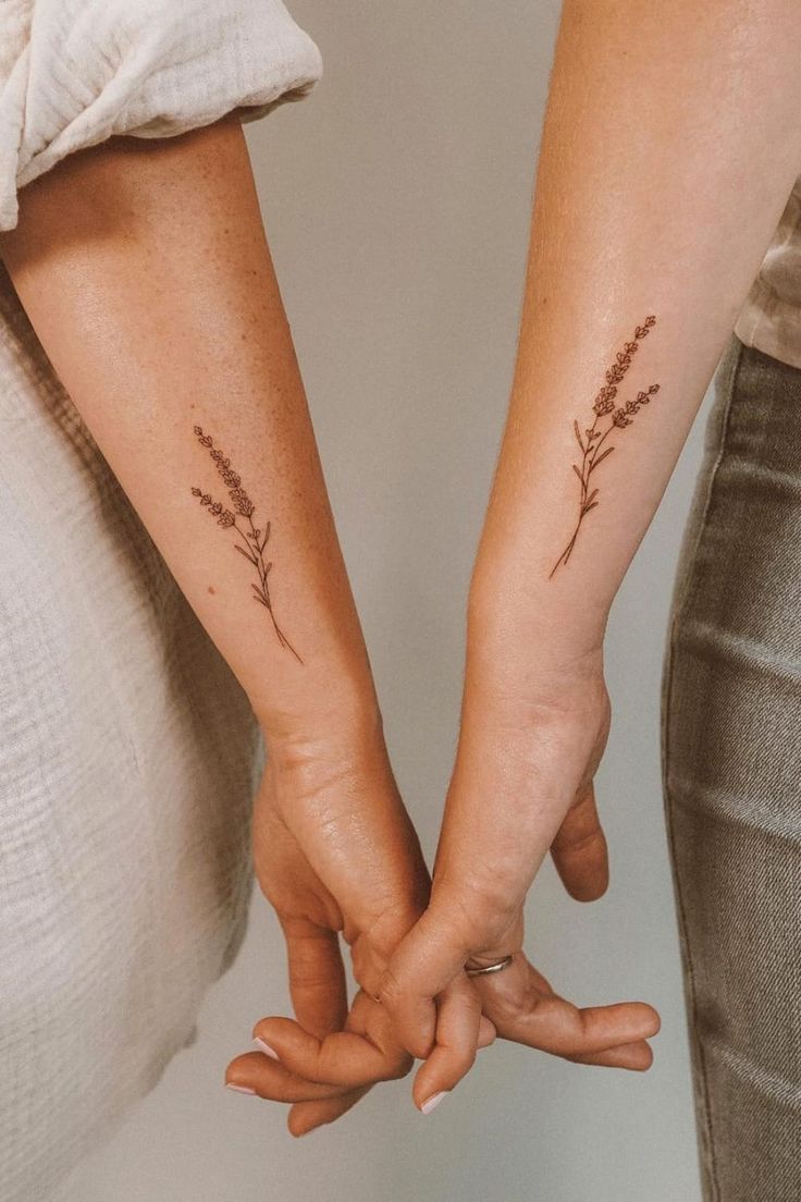 two people holding hands with small tattoos on their arms and the other hand behind them