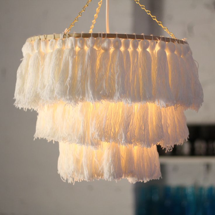 a white chandelier hanging from a ceiling with fringes on the top and bottom