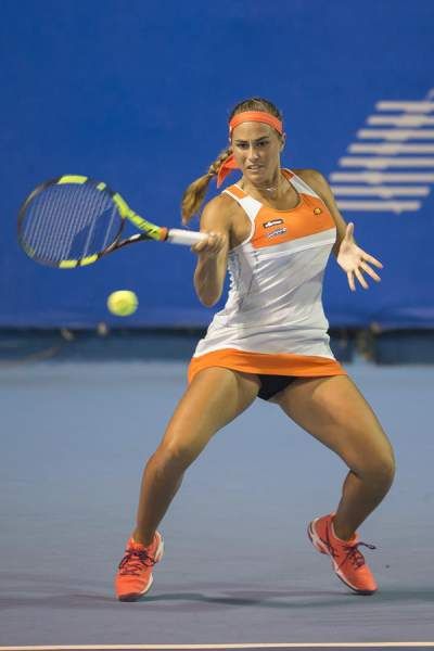 a female tennis player is swinging her racket to hit the ball on the court