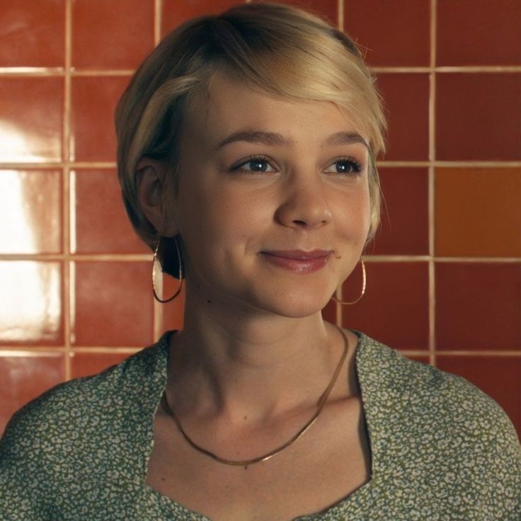 a woman standing in front of a tiled wall with her eyes closed and smiling at the camera