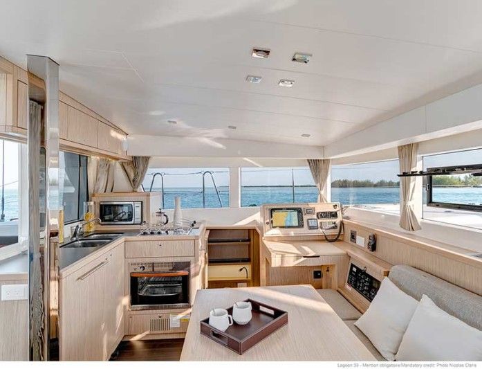 the interior of a sailboat with lots of wood furniture and windows looking out on the water