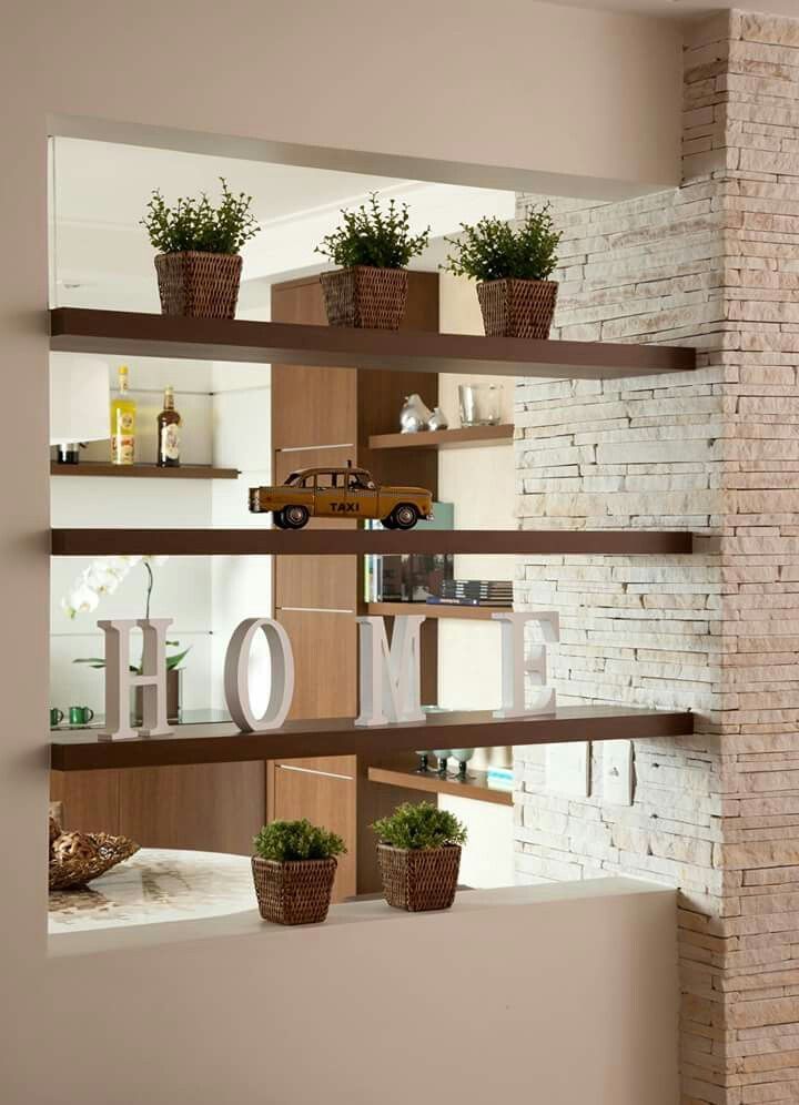 some plants are sitting on shelves in a room with a brick wall behind them and the word home spelled out