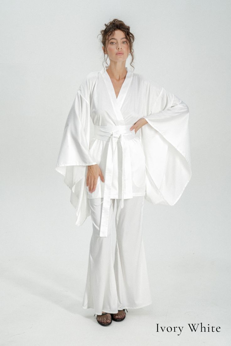 Indulge in luxury with our exquisite long bridal robe, crafted from sumptuous silk satin, perfect for adding elegance to your wedding day preparations. Elevate your bridal ensemble with our bridal kimono robe, designed for timeless sophistication and unparalleled comfort on your special day. ✂ About us: ♥ Est. 2017 ♥ Based in Lincolnshire, UK ♥ Handmade in Europe ♥ Small family run brand ♥ Handmade in Europe ♥ Sustainable and ethical production ♥ We support local craftsmanship ♥ Sizes for all body types ✂ About PJs: * Obi tie belt * Long wide kimono sleeves * Hidden side kimono pockets * Inside loops * High-waisted trousers *Trouser pockets * Silky Satin ✂ Shipping: * Fast UK delivery in 1 - 2 days * We ship worldwide! * Returns accepted 🌸 Due to high demand processing time for custom and Elegant White Floor-length Kimono, Elegant White Bridal Kimono, White Wedding Gown With Kimono Sleeves, White Kimono Sleeve Robe For Wedding Night, White Robe With Kimono Sleeves For Wedding Night, White Kimono Sleeve Wedding Robe, White Kimono With Kimono Sleeves For Wedding Night, White Long Sleeve Sleepwear For Wedding, White Satin Sets For Wedding Night