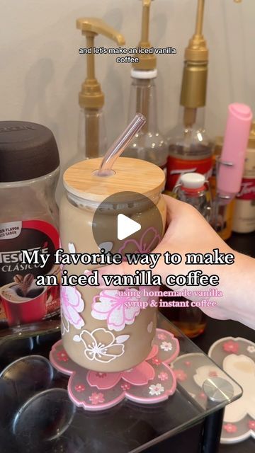 a person holding a cup with a straw in it on top of a counter next to other items