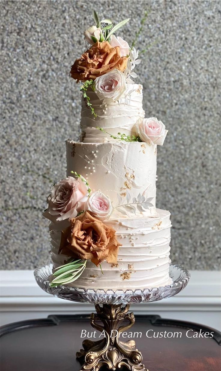 a three tiered wedding cake with flowers on top