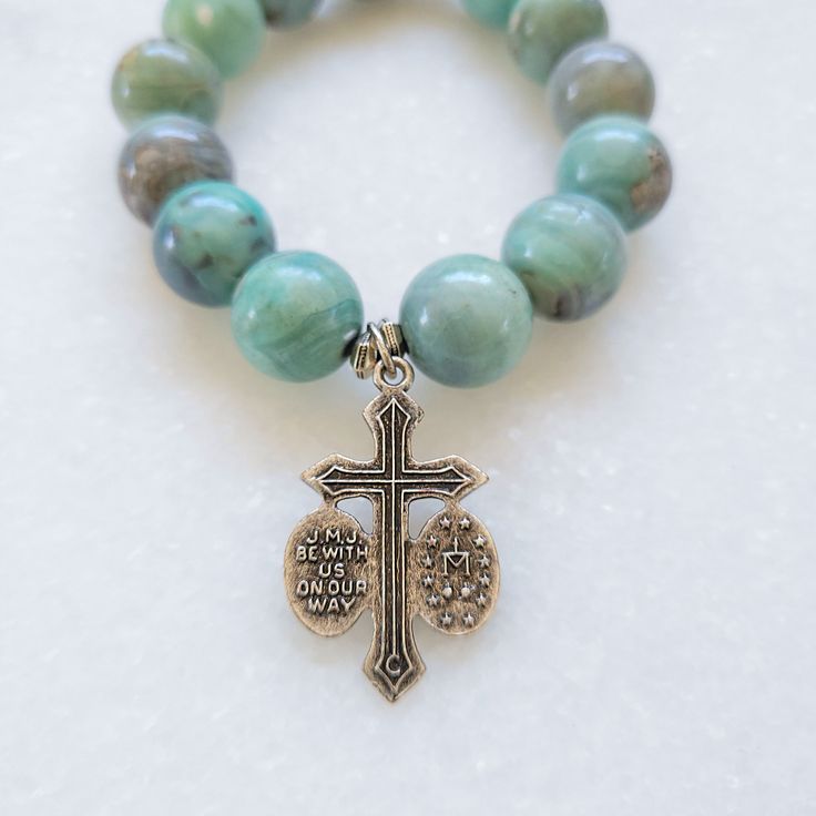 These exquisite beads truly encapsulate the beauty of the emerald coast. Each turquoise bead is naturally unique resulting in a stunning array of tranquil aqua colors. The bracelet is expertly strung on a durable elastic band for the perfect fit that complements any look. The Bracelet features a Jesus/Mary/Joseph vintage crucifix silver medal with "JMJ Be With Us On Our Way" on the back. Spiritual Stretch Bracelet With Round Amazonite Beads, Spiritual Stretch Bracelet With Amazonite Beads, Spiritual Amazonite Stretch Bracelet With Round Beads, Turquoise Amazonite Bracelet With 8mm Beads, Turquoise Rosary Bracelet With Round Beads, Turquoise Spiritual Rosary Bracelet With Round Beads, Spiritual Turquoise Rosary Bracelet With Round Beads, Turquoise Amazonite Beaded Bracelet With 8mm Beads, Turquoise Spiritual Stretch Bracelet With 8mm Beads