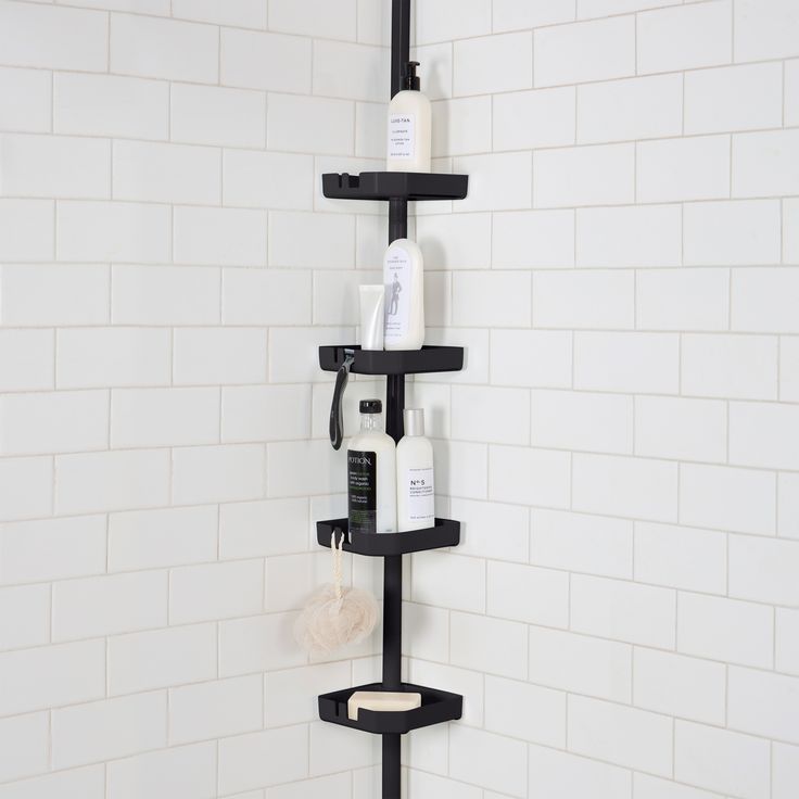 there is a black shelf in the shower that has several bottles and soaps on it