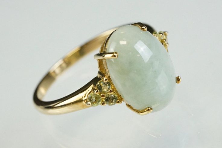 Beautiful vintage ring set with an oval pale green jade cabochon with three small round peridot stones prong set to each shoulder. The jade has some delicate marbling and the peridots set this off elegantly. Cabochon is 1 x 1.4cm. Ring shank has a slight flair to the head and is marked 9ct gold. The ring has been carefully cleaned to be loved all over again.  Ring size: UK P; US 7 1/2. Total width of head of ring 1.4 x 1.4cm (3.7gm weight) Shipping and packaging: Your ring will be beautifully boxed with a ribbon (vintage box in photos is for display purposes only and actual packaging is shown separately). Sent within 1-3 working days.  If you're in the UK your Joyful delivery will be sent by Royal Mail 1st class tracked. Etsy will let you know when it's on its way. Overseas deliveries are Elegant Green Cabochon Moonstone Ring, Green Oval Moonstone Wedding Ring, Oval Green Moonstone Wedding Ring, Green Oval Prehnite Rings, Chain Threader Earrings, Beautiful Rings Vintage, Marcasite Ring, Ring Shank, Peridot Stone