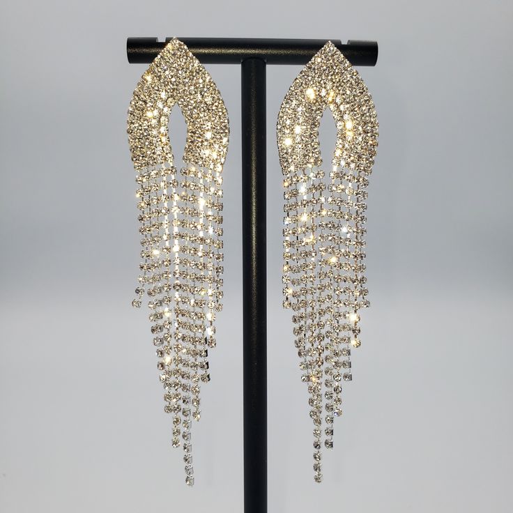 Sparkly Silver rhinestone, Marquise tip rhinestone top. With long rhinestone tassels at bottom 4 1/2" long Material: Zinc Alloy, Crystal, Rhinestone Hypoallergenic Silver Crystal Earrings With Rhinestone Fringe, Glamorous Silver Crystal Earrings With Rhinestone Fringe, Glamorous Gold Tassel Earrings With Rhinestones, Long Drop Rhinestone Party Jewelry, Gold Rhinestone Tassel Dangle Earrings, Party Jewelry With Rhinestones In Long Drop Shape, Party Jewelry With Long Drop Rhinestones, Glamorous Rhinestone Dangle Chandelier Earrings, Crystal Chandelier Earrings With Rhinestone Fringe