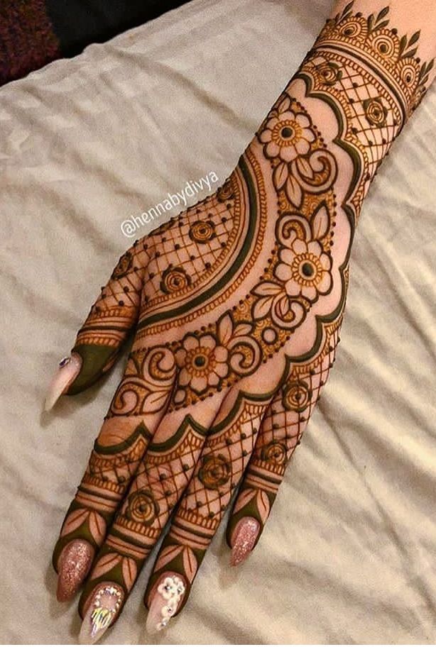 the hand is decorated with henna designs and has an arrow pointing to the right