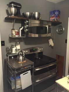 a kitchen with stainless steel appliances and shelves on the wall above an open stove top oven