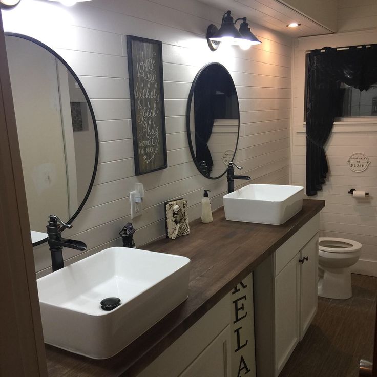 a bathroom with two sinks and mirrors on the wall next to a wooden counter top