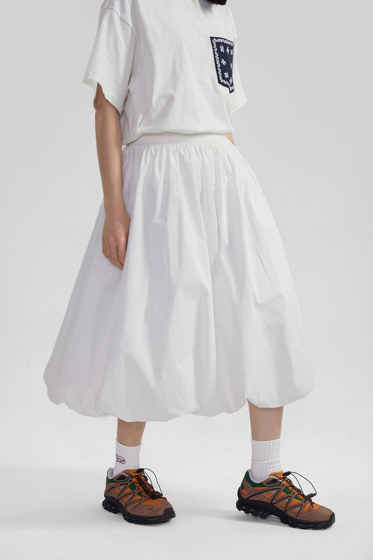 Elevate your wardrobe with this High-Waisted Pleated Slip Midi Skirt – a timeless piece blending a touch of retro charm with modern sophistication. Meticulously crafted from 100% cotton, this skirt features an array of finely tailored pleats that create a voluminous silhouette, enhancing its graceful movement. The solid color and subtle texture offer a versatile base for an array of styling options. A natural waistline and A-line cut promote a flattering fit, while practical side pockets bring a Voluminous Skirt Outfit, White Relaxed Fit Skirt With Elastic Waistband, White Skirt With Elastic Waistband And Relaxed Fit, High Waist Relaxed Skirt For Daywear, High Waist Skirt With Elastic Waistband For Daywear, Relaxed High Waist Skirt For Daywear, Flared Skirt With Fitted Waist And Lining, Modern Flared Skirt For Spring, High Waist Pleated Skirt For Daywear