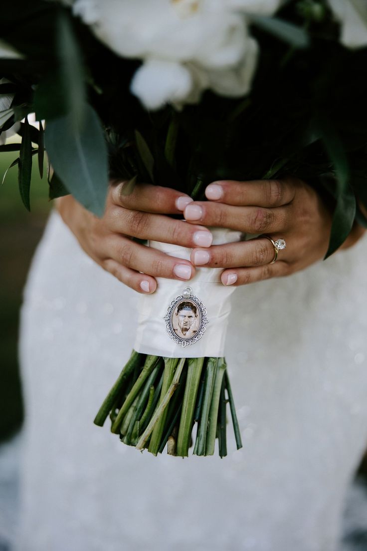 a woman holding a bouquet of flowers in her hands with the bride's wedding ring on it