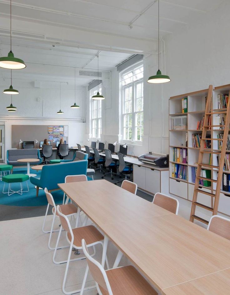 an office with tables, chairs and bookshelves in the middle of the room