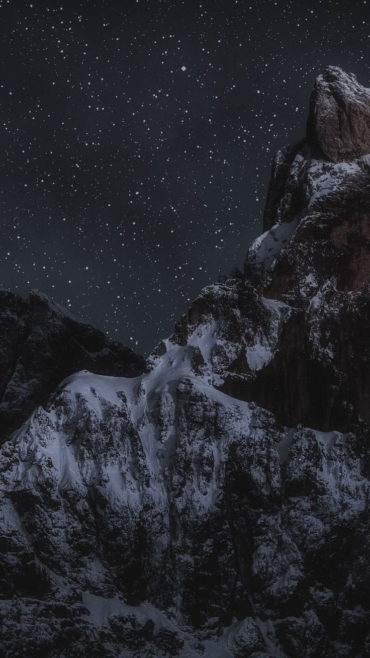 the night sky is filled with stars above some snow covered mountain tops and mountains in the foreground