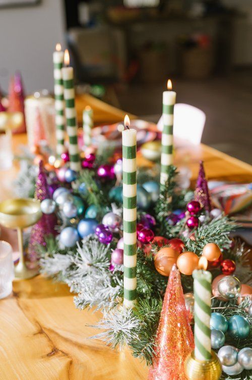 a table topped with lots of candles next to christmas decorations on top of a wooden table