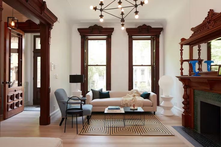 a living room filled with furniture and a fire place in front of two large windows