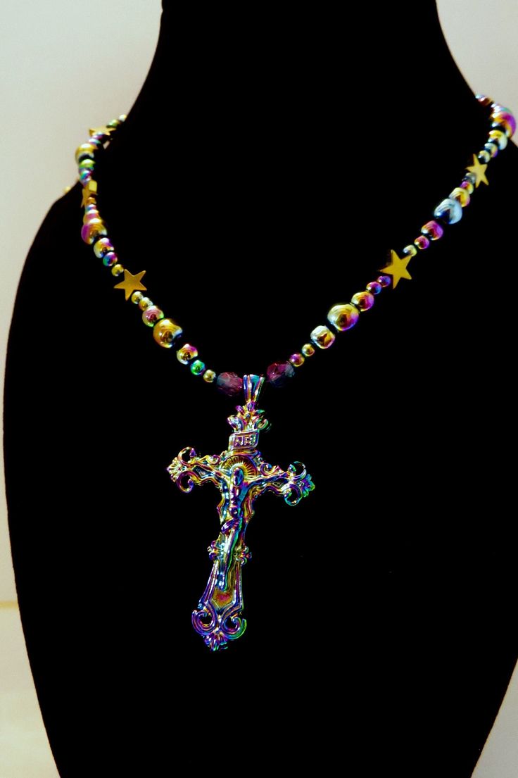 This item is an original design by me Reflecting all the colors of the rainbow, this necklace features electroplated round glass beads and an ornate metal crucifix. Star-shaped beads are gold-colored synthetic hematite. Two of the beads nearest the crucifix are Czech glass. Semi-flexible base is beading wire. Lobster clasp and jump rings are gold plated.  Please see images for scale, etc. Necklace is approximately 23" long with a 2" extender. Cross is approximately 2" in height. Total 1.2 oz/34 g in weight. Please see my shop for more religious jewelry, rosaries, animal sculptures, and more! Thank you! Stars Gold, Crucifix Necklace, Beading Wire, Religious Jewelry, Animal Sculptures, Jewelry Handmade, Star Shape, Jump Rings, Czech Glass