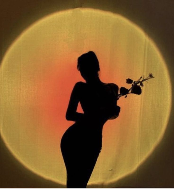 the silhouette of a woman holding flowers in front of a sun