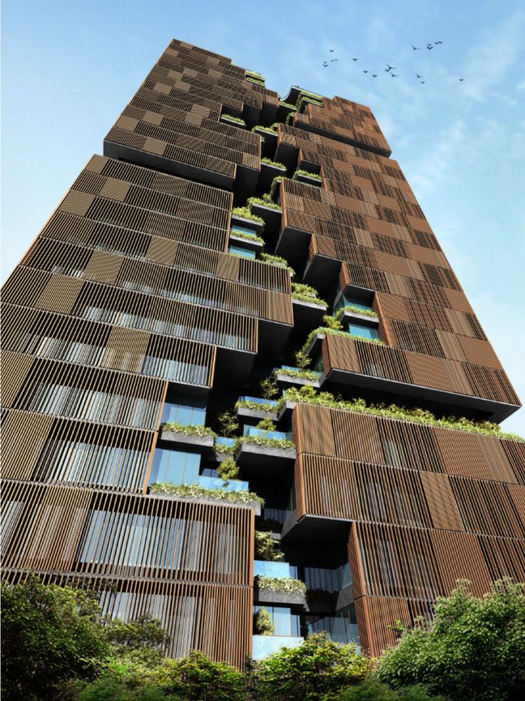 a tall building with lots of windows and plants growing on it's sides, against a blue sky