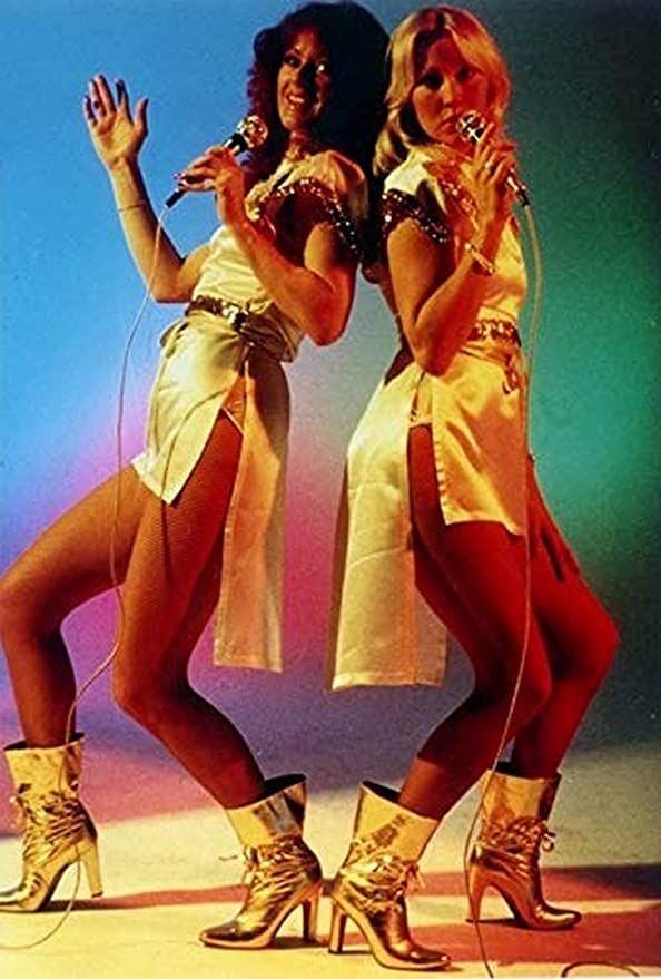 two women in short skirts and high heeled boots are posing for the camera with their arms around each other