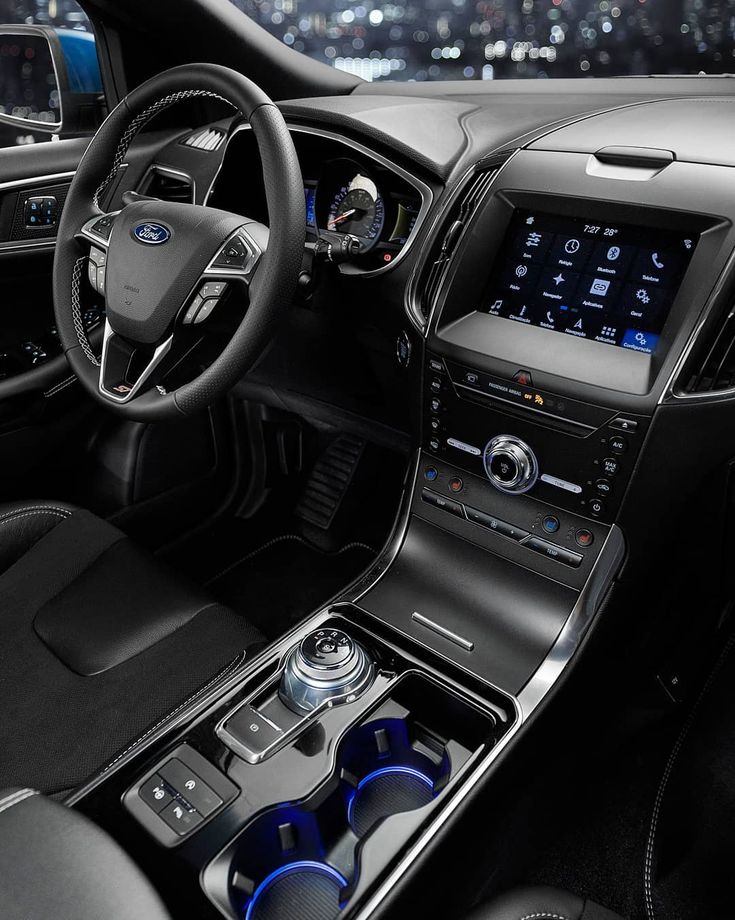 the interior of a car with black leather and blue trims, including steering wheel controls