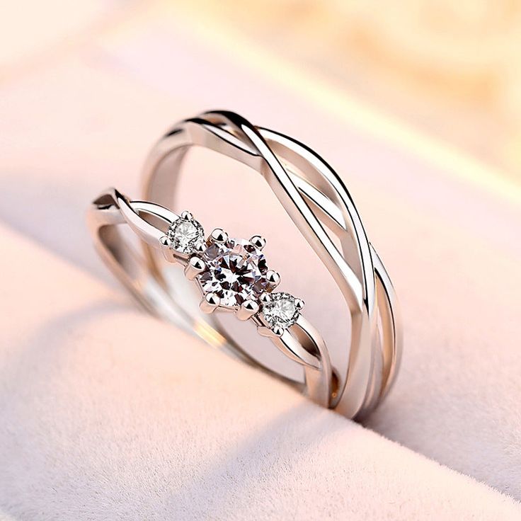 two white gold wedding rings with diamonds on the top and one diamond in the middle