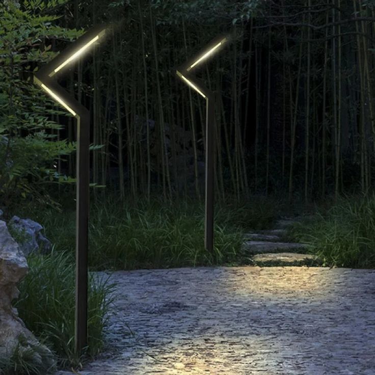 three lights are lit up in the middle of a path between two rocks and trees