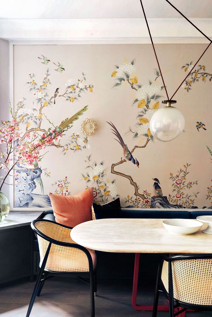 a table with chairs and vases on it in front of a floral wallpaper