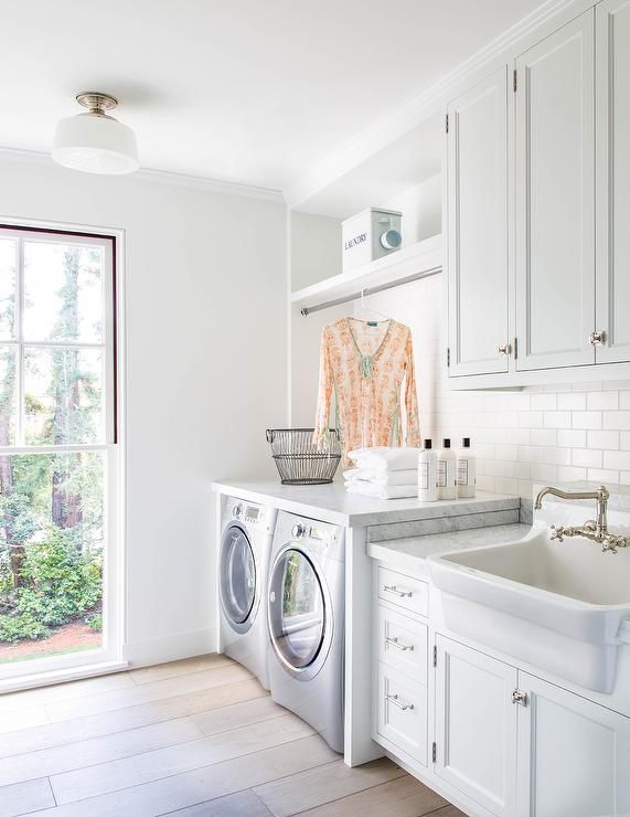 a kitchen with white cabinets and washer and dryer next to a large window