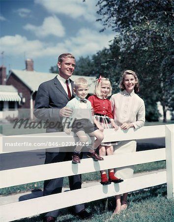 a man and two children are sitting on a white fence with their father standing next to them