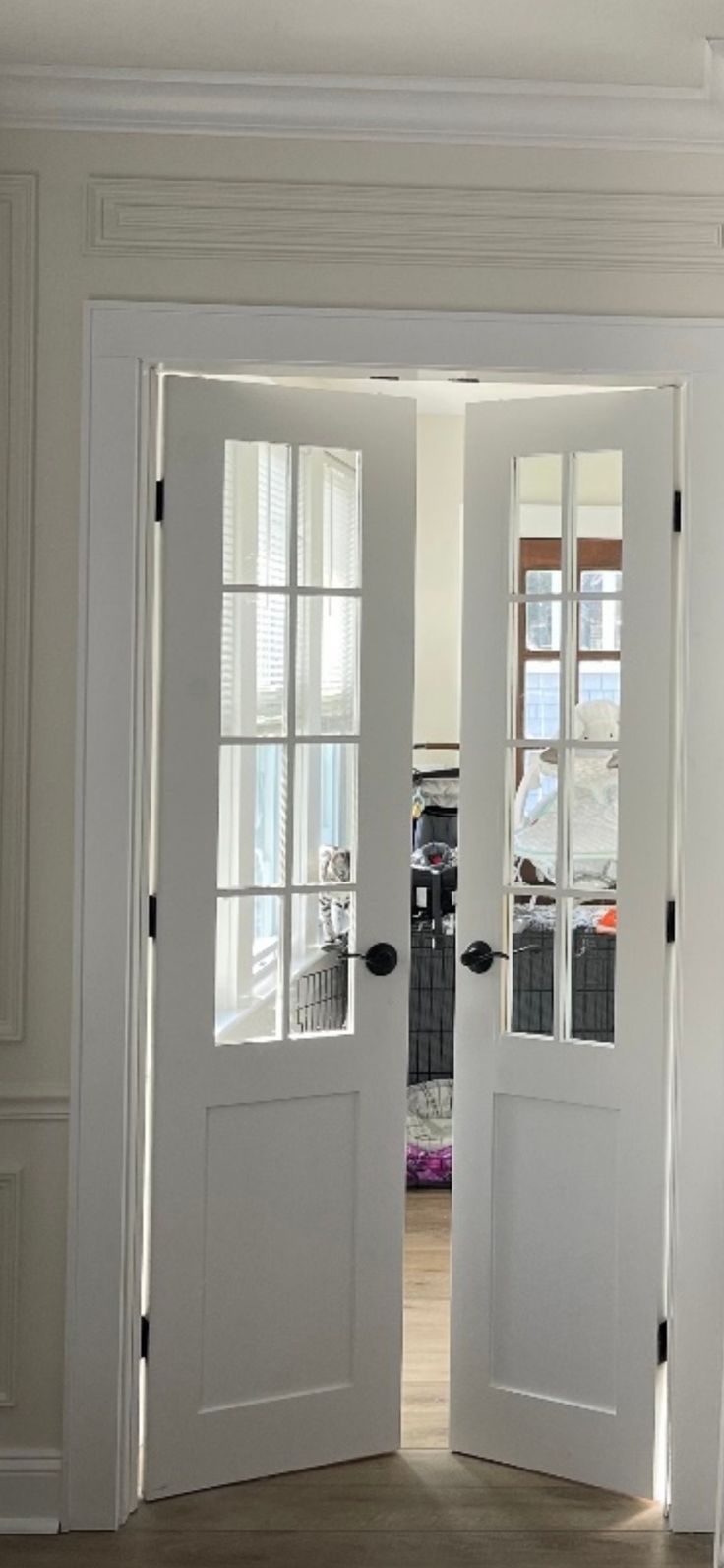 two white doors are open in a room with wood flooring and windows on the wall