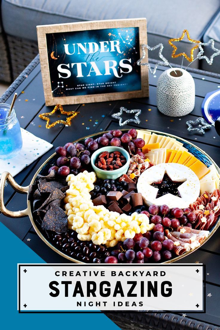 Moon & Stars themed charcuterie board, Under the Stars party sign, and decorative metallic pipe cleaner stars for a Backyard Stargazing Night Space Foods Party, Space Theme Dinner Party, Galactic Party Food, Solar Party Food, Outer Space Fruit Platter, Full Moon Charcuterie Board, Solar Eclipse Cheese Board, Two The Moon Party Favor Ideas, Galaxy Fruit Platter