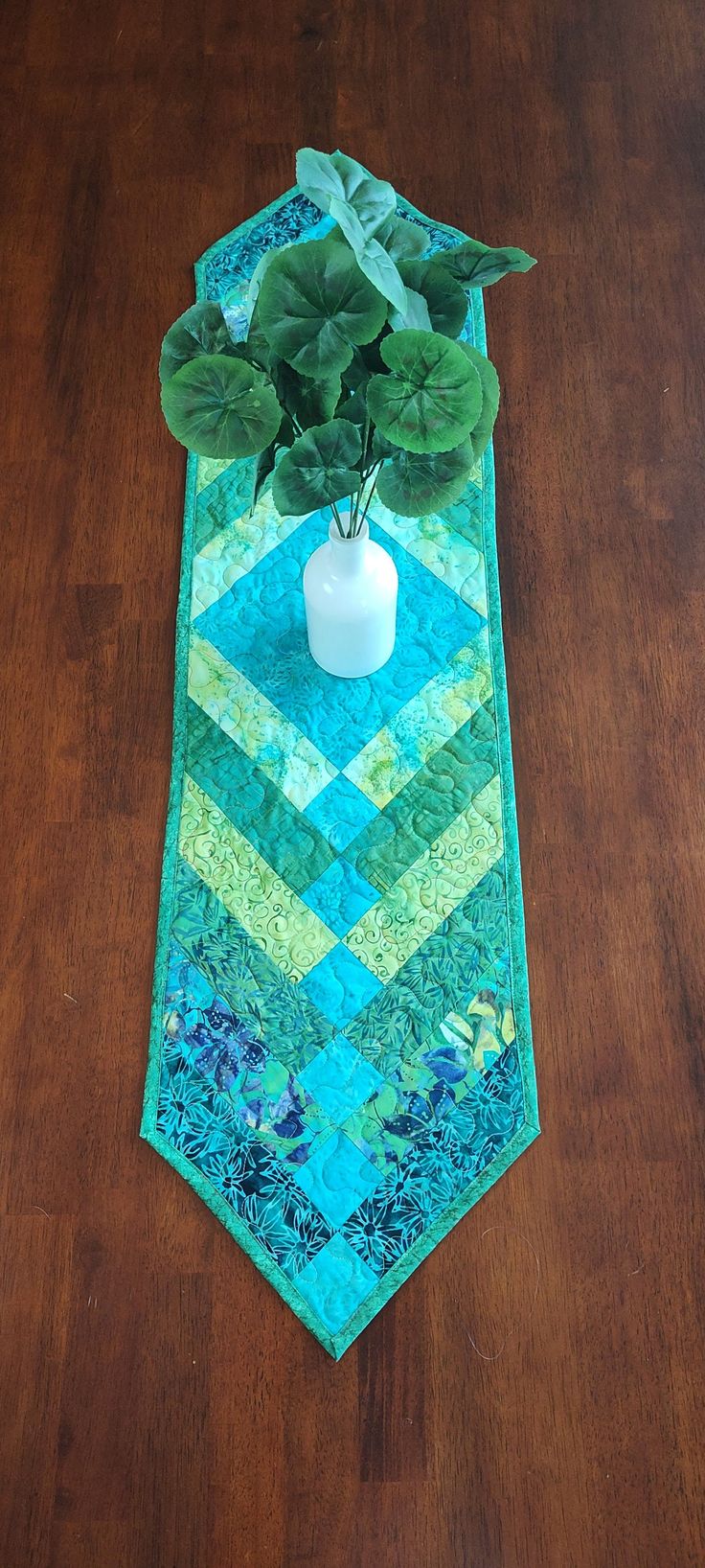 a potted plant sitting on top of a wooden table next to a blue and green tie