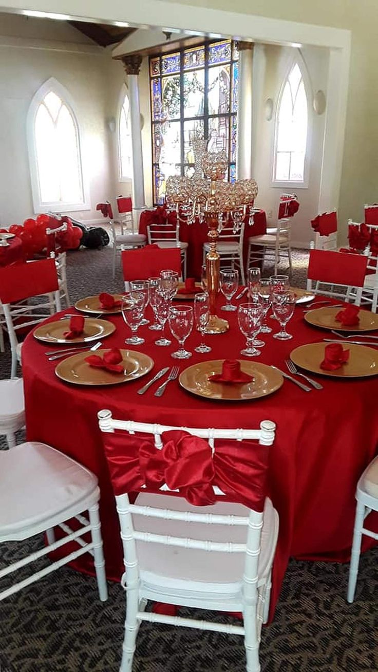 a dining room with red table cloths and white chairs