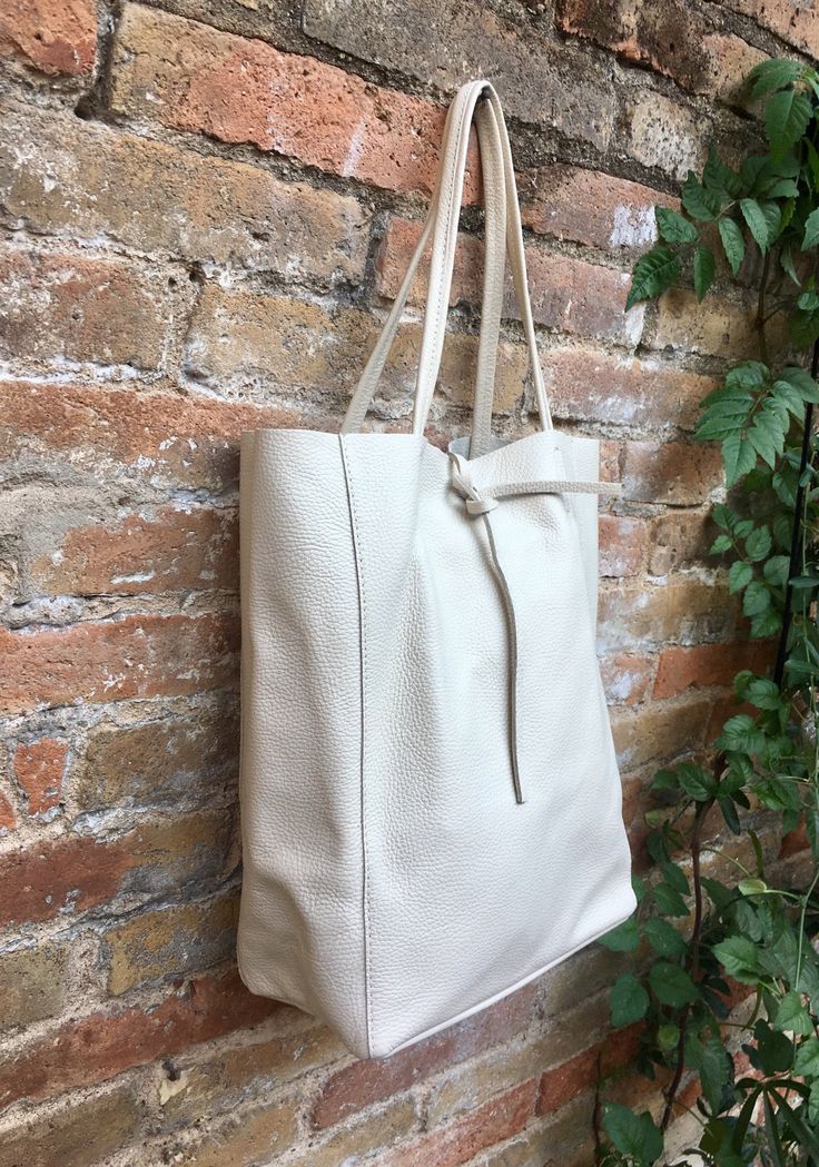 Large tote leather bag in a very light BEIGE shade. Broken white shopper bag natural GENUINE leather. Large enough for books or a laptop, tablet, cosmetics bag etc. Creamy white Leather shopper. The inside of the bag is not lined (although properly finished!) . We added a small leather pouch on the inner part of the bag . The bag can be closed by 2 leather straps attached to each side. Excellent quality soft but strong genuine leather. The color of the bag in this listing is a very light beige c Bag For Books, Tote Leather Bag, Suede Tote Bag, Slouch Bags, Tablet Bag, Small Coin Purse, White Tote Bag, Broken White, Cosmetics Bag