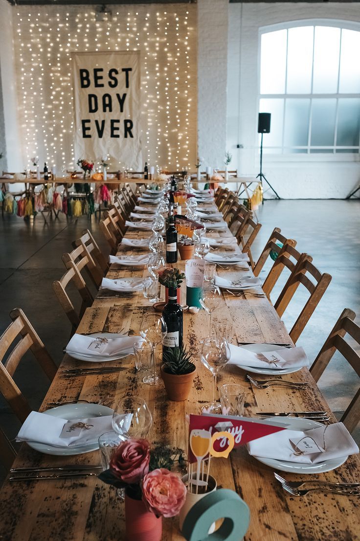 a long wooden table with place settings and flowers on it in front of a sign that says best day ever