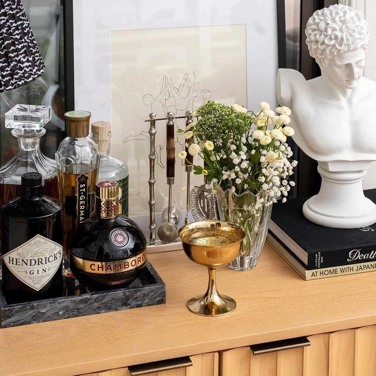 a table topped with bottles and vases filled with flowers next to a busturine