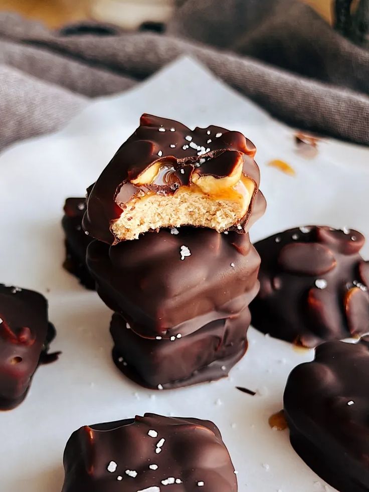 several chocolate covered desserts are on a white plate with sprinkles and one has a bite taken out