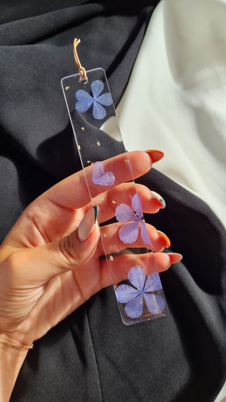 a woman's hand holding an acrylic case with purple flowers on it