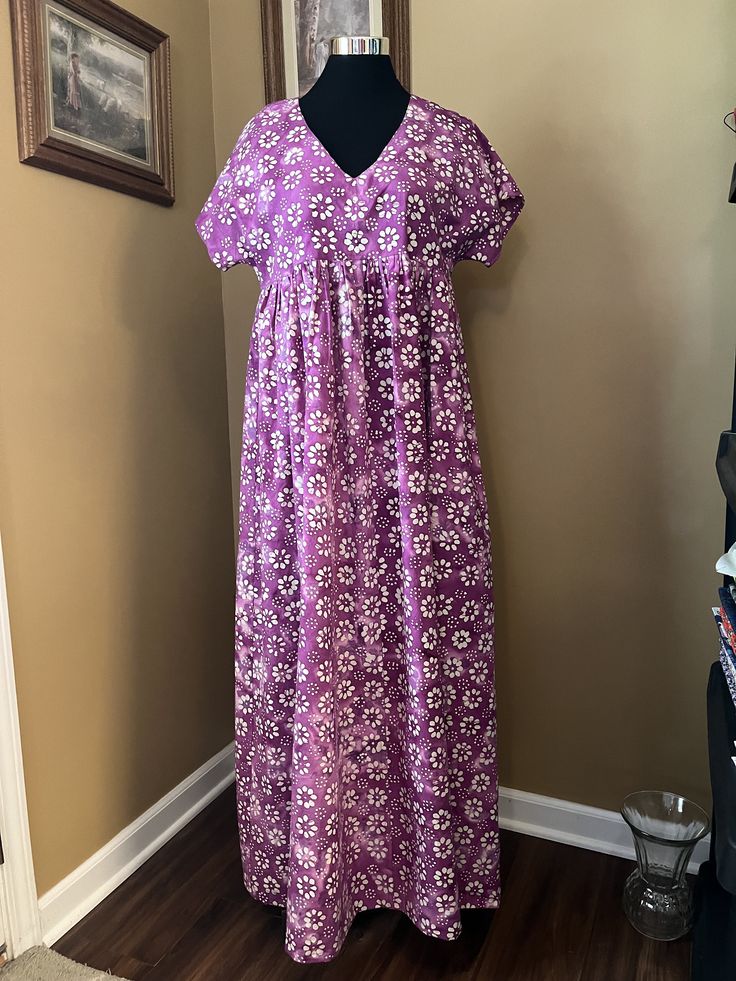 "This is a hand crafted maxi dress with a high empire waist, v neck and a full gathered skirt.  It is made of a lovely tropical looking purple batik, cotton fabric. It has a nice casual look for home, lunch date, hanging out at the beach or even to wear on a cruise. It is a ladies size large, 14-16.  Please, review the measurements for the size below to check the fit, before ordering. Bust size 36-38. Hip size 38-40. Length of the dress is about 56 1/2\" long.  This measurement is taken from the Summer V-neck Maxi Dress With Batik Print, Summer Floor-length Maxi Dress With Batik Print, Summer Batik Print Floor-length Maxi Dress, Bohemian Empire Waist Maxi Dress For Vacation, Bohemian Maxi Dress With Empire Waist For Vacation, Purple V-neck Sundress For The Beach, Flowy Batik Print Maxi Dress, V-neck Batik Print Beach Dress, Bohemian V-neck Maxi Dress With Batik Print