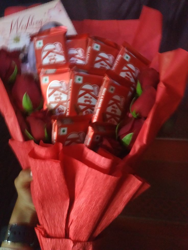 a person holding a bouquet of red roses and chocolate bars with chinese writing on them