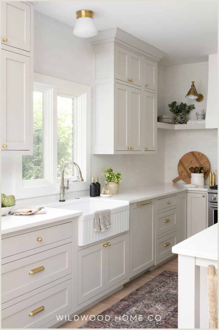 a kitchen with white cabinets and gold hardware on the doors, windows, and counter tops