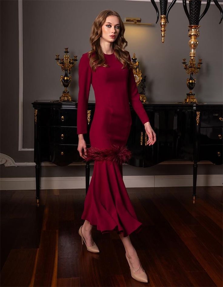 Make a stunning entrance in this exquisite burgundy evening gown, designed to capture attention with its unique feather-trimmed hemline. The dress features a fitted silhouette that gracefully flows into a flared skirt, adding a touch of sophistication and drama. The long sleeves and minimalist design balance the luxurious texture of the feather trim, making this gown perfect for upscale events, galas, or formal occasions. Crafted with meticulous attention to detail, this dress ensures you will s Floor-length Evening Dress With Feather Trim, Floor-length Feather Trim Evening Dress, Elegant Floor-length Evening Dress With Feathers, Elegant Evening Dress With Feather Trim For Gala, Elegant Feather Trim Evening Dress For Gala, Elegant Gala Evening Dress With Feather Trim, Formal Evening Dress With Feather Trim, Elegant Formal Evening Dress With Feathers, Elegant Fitted Evening Dress With Feather Trim