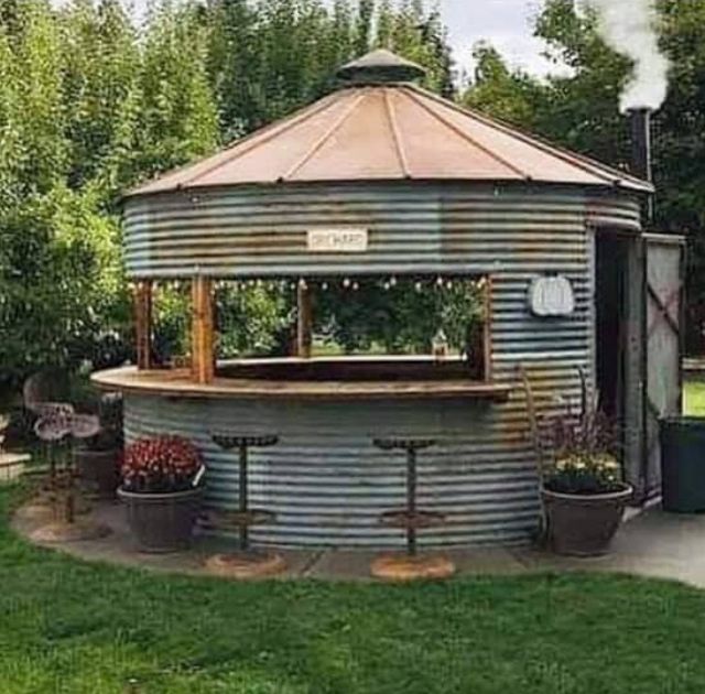 an outdoor bar in the middle of a grassy area with potted plants and trees