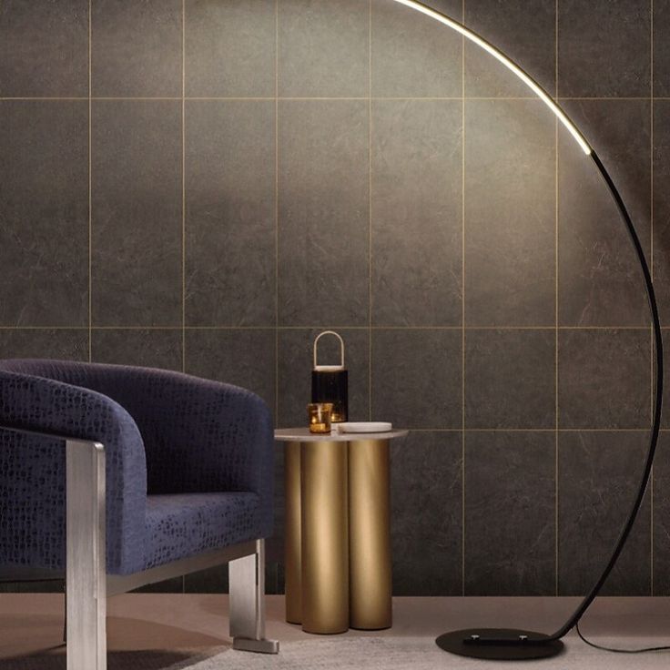 a modern floor lamp next to a chair and table in a room with tiled walls