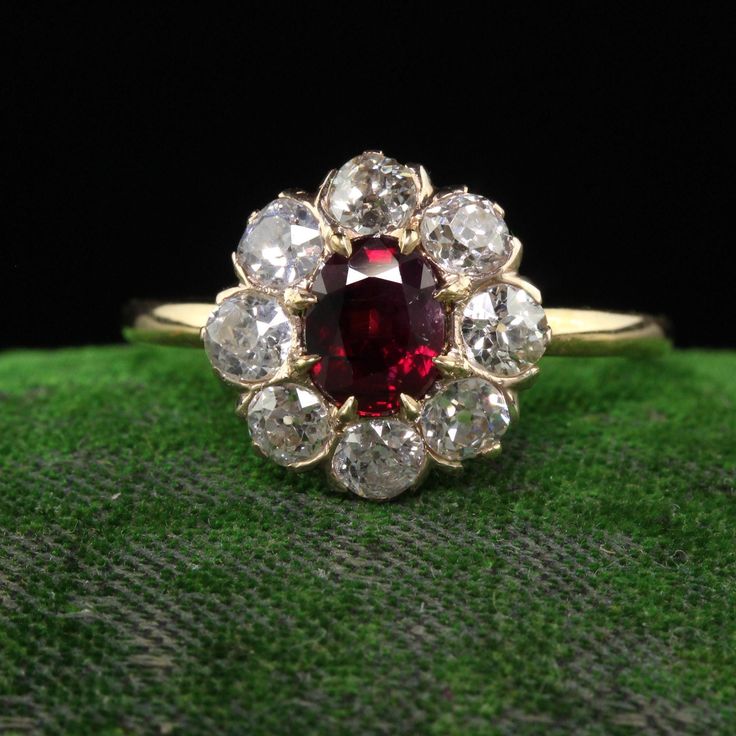 a red and white diamond ring sitting on top of a green cloth